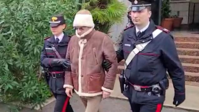Top Mafia boss Matteo Messina Denaro, center, is seen  with Italian Carabinieri officers soon after his arrest at a private clinic in Palermo, Sicily, after 30 years on the run. 