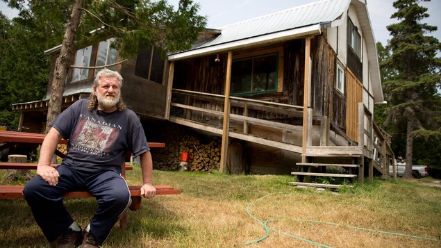 Uh homme de 60 ans assis sur une table de picnik devant une maison en bois Uh homme de 60 ans assis sur une table de picnik devant une maison en bois