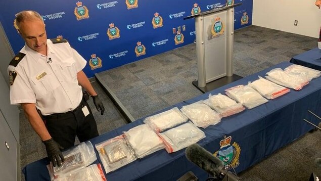 Un policier pose devant des paquets de drogue étalés sur une table au quartier général de la police.