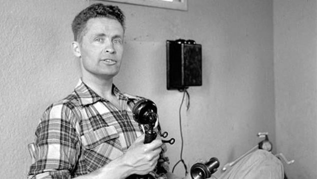 Max Ward, assis contre un mur, tient un vieux téléphone.