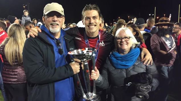 Maxim et ses parents sont sur le terrain de soccer et tiennent la coupe de la North American Soccer League (NASL). Maxim et ses parents sont sur le terrain de soccer et tiennent la coupe de la North American Soccer League (NASL).