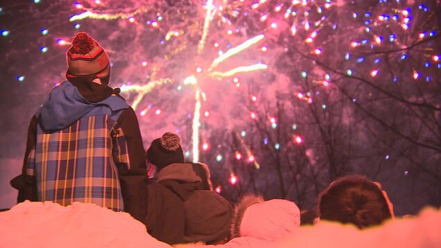 Des gens regardent des feux d'artifice en hiver.
