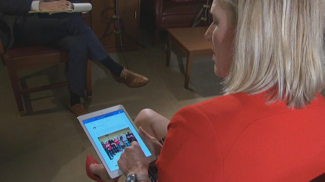 Catherine McKenna lit sur une tablette des messages publiés sur les réseaux sociaux.