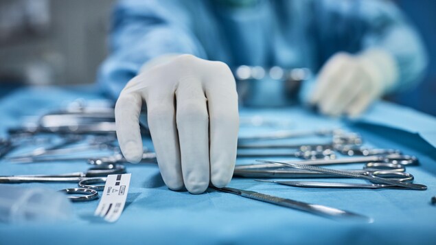 Un chirurgien prend un outil sur un plateau d'opération.