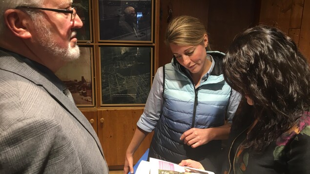 Mélanie Joly regarde un livre qui lui est présenté par une femme.