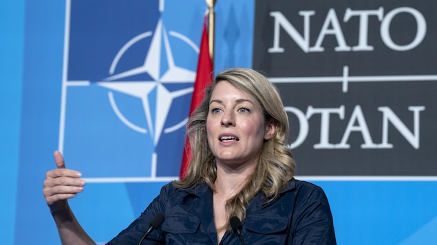 Mélanie Joly prononce un discours. On voit le logo de l'OTAN derrière elle. 