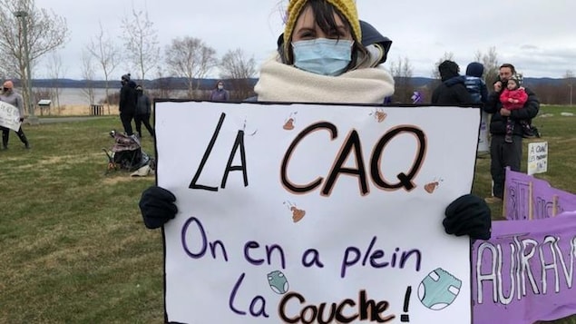 Mélissa Bernier porte une affiche où on peut lire "La CAQ on en a plein la couche"