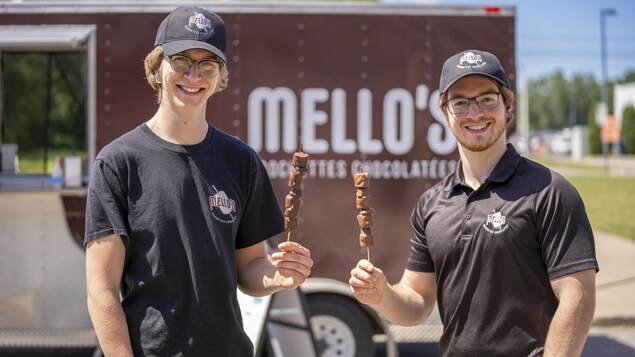 Les deux jeunes hommes avec des brochettes de guimauves et de chocolat.