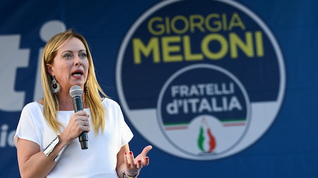 意大利总理梅洛尼站在竞选海报前。