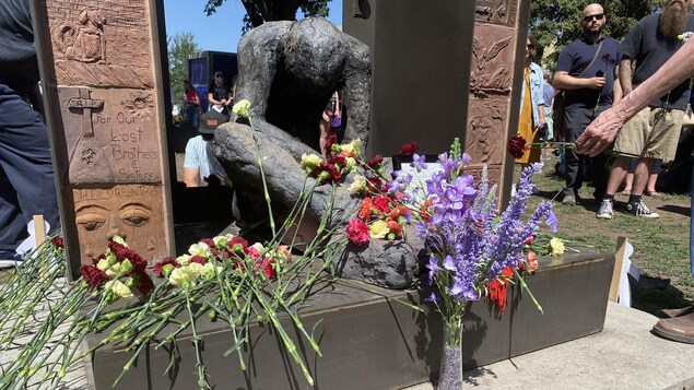 Des gerbes de fleurs déposées sur un monument commémoratif.