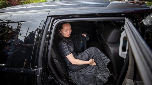 Une femme en robe entre dans une voiture noire. 