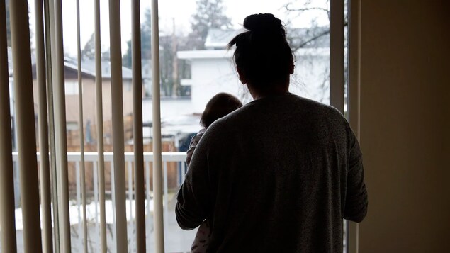 Une mère avec son bébé devant une fenêtre.