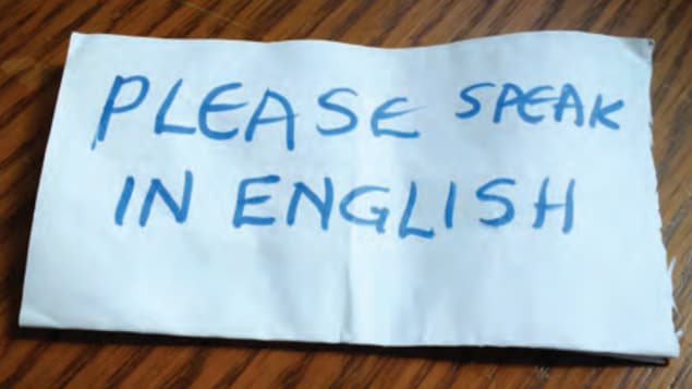 Un bout de papier sur lequel on peut lire en anglais : « parlez anglais SVP ».