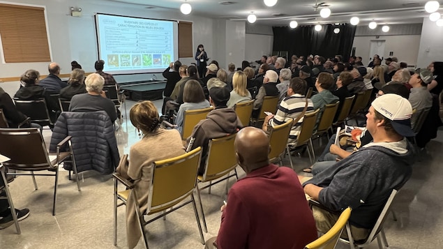 Une salle pleine de gens qui regardent un écran.