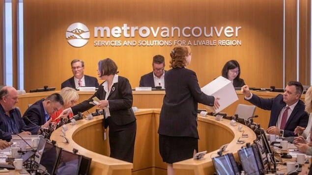 Un vote a lieu chez le conseil d'administration du Grand Vancouver, avec des employés qui collectent les bulletins de vote.