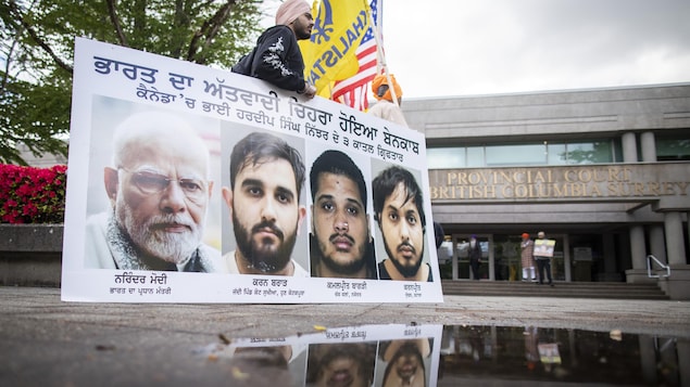 Un partisan tenant une pancarte la photo du premier ministre indien, Narendra Modi, et celles des trois accusés.