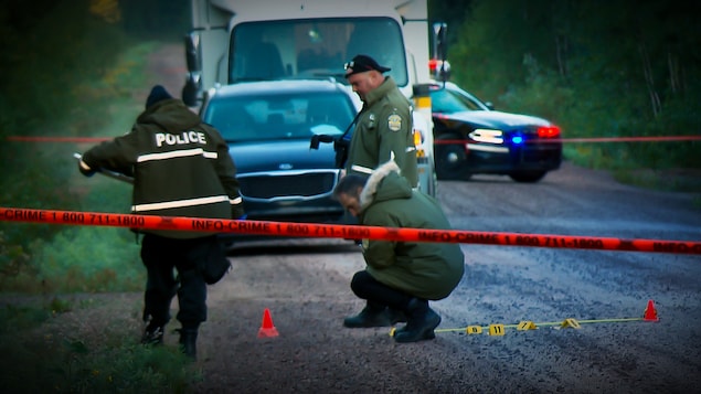 Des policiers colligent des indices sur la scène du crime.