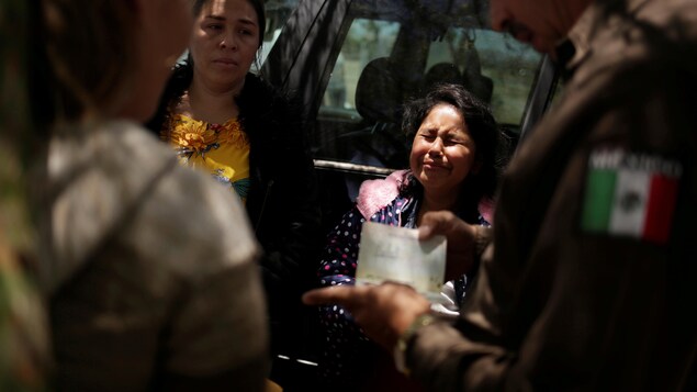 Une jeune fille pleure pendant qu'un agent de la garde nationale mexicaine regarde ses papiers.