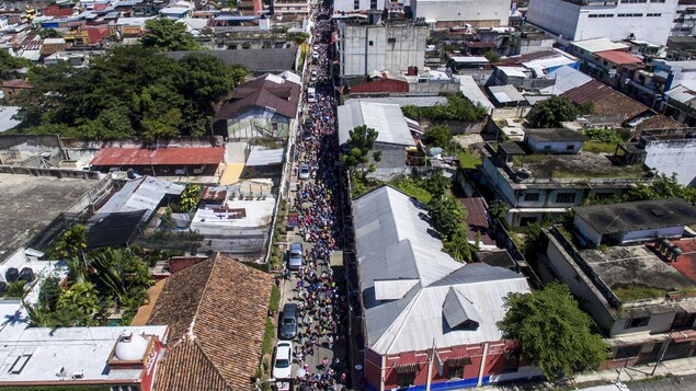 Une vue aérienne d'une colonne de migrants traversant une ville.