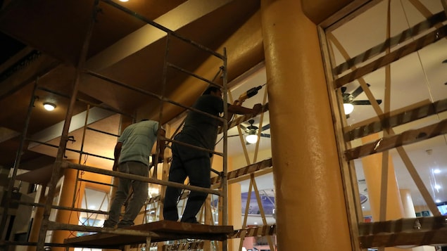 Deux employés juchés sur un escabeau effectuent des travaux. Deux employés juchés sur un escabeau effectuent des travaux.