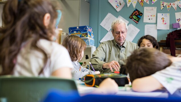L'aîné Yves Bernard est entouré de jeunes enfants de maternelle, alors que ceux-ci sont occupés à dessiner. L'aîné Yves Bernard est entouré de jeunes enfants de maternelle, alors que ceux-ci sont occupés à dessiner.