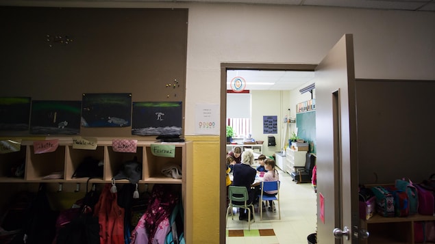 À travers la porte d'une classe, on aperçoit de jeunes élèves de la maternelle qui écoutent Suzanne Lavallée et Lydia De Melo. À travers la porte d'une classe, on aperçoit de jeunes élèves de la maternelle qui écoutent Suzanne Lavallée et Lydia De Melo.