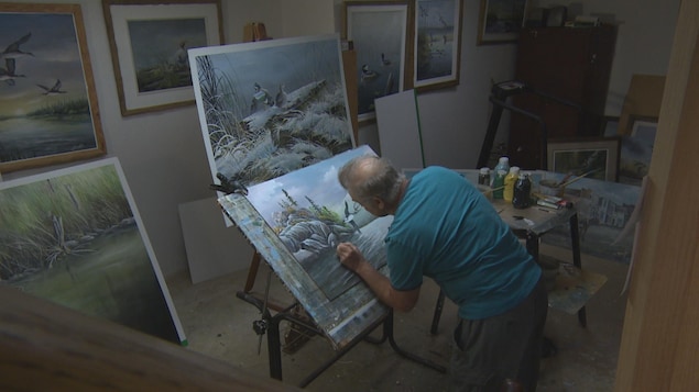 Un homme peinture un paysage devant un chevalet. Un homme peinture un paysage devant un chevalet.