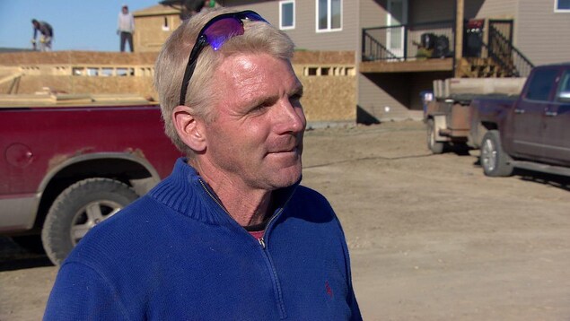 Micheal Groulx parle en entrevue devant une maison avec une remorque derrière. Micheal Groulx parle en entrevue devant une maison avec une remorque derrière.
