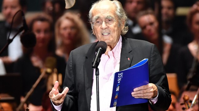 L'homme parle devant un micro avec un dossier dans les mains.