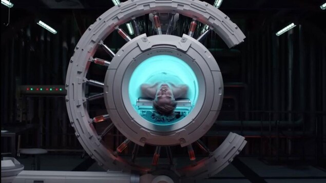 Un homme dort dans une machine futuriste, ressemblant à un appareil de résonance magnétique.