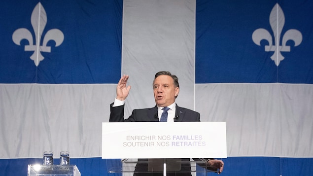François Legault, premier ministre du Québec, prononce un discours devant un immense drapeau du Québec