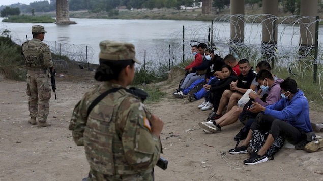 Des migrants surveillés par des membres de la Garde nationale américaine.