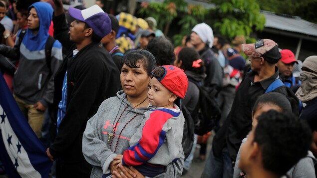 Des dizaines de migrants, dont une femme tenant un enfant dans ses bras, attendent à la frontière. Des dizaines de migrants, dont une femme tenant un enfant dans ses bras, attendent à la frontière.