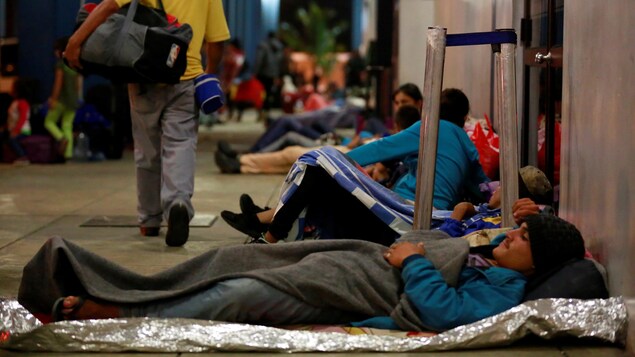 Des migrants vénézuéliens attendent sur des couvertures de survie dans les couloirs, à la frontière entre l'Équateur et le Pérou. Des migrants vénézuéliens attendent sur des couvertures de survie dans les couloirs, à la frontière entre l'Équateur et le Pérou.