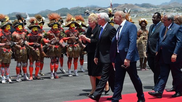 Le vice-président regarde des membres de tribus papoues l'accueillir sur le tarmac de l'aéroport.