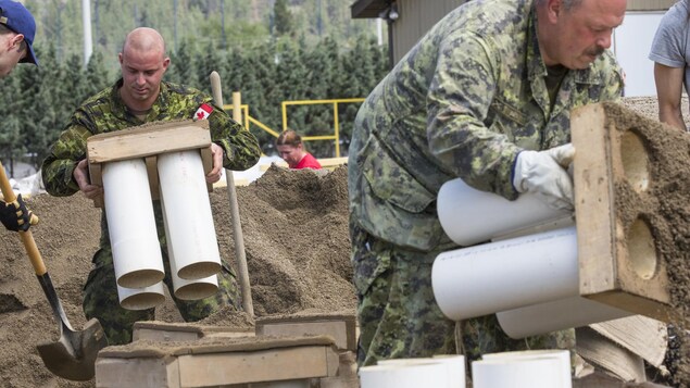 Des militaires s'activent à contruire une digue avec des poches de sable et du matériel de retenue pour contrer la crue des eaux à Grand Forks en Colombie-Britannique. Des militaires s'activent à contruire une digue avec des poches de sable et du matériel de retenue pour contrer la crue des eaux à Grand Forks en Colombie-Britannique.