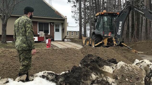 Un soldat canadien supervise des travaux près d'une résidence.