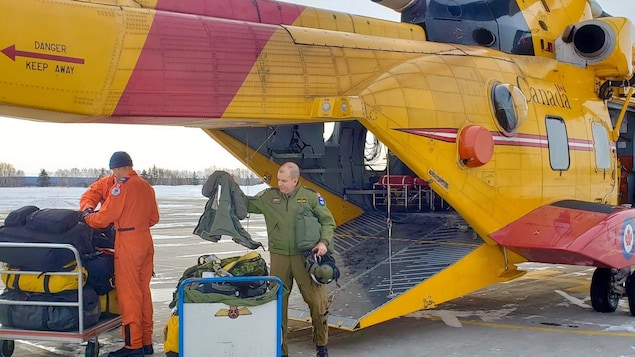 Trois militaires transportent du matériel à l'intérieur d'un hélicoptère canadien.