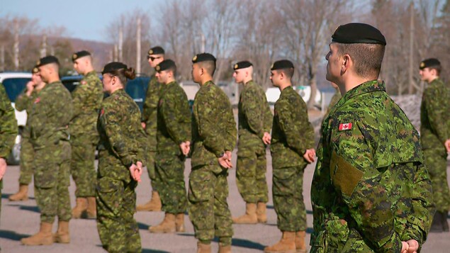 Des militaires, en uniformes, se tiennent en rang.