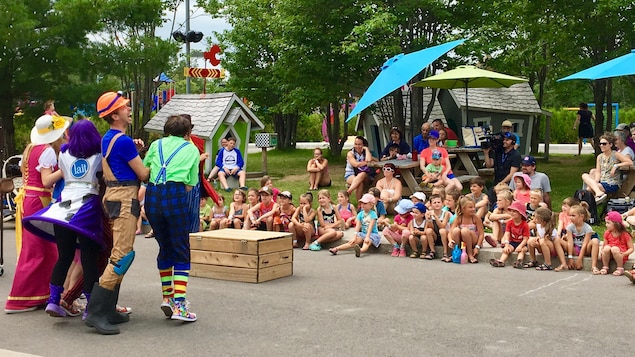 Des enfants assis sur le sol devant une équipe de clowns professionnels.