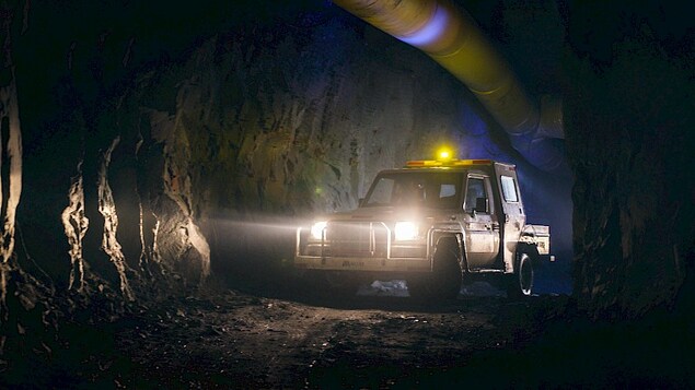 Un camion éclaire une galerie de mine souterraine.