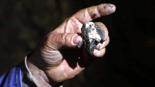 Gros plan sur un petit morceau de minerai dans la main d'un homme.