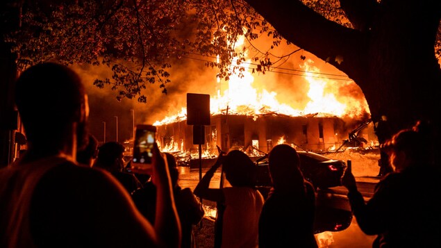 Des curieux regardent un bâtiment en proie aux flammes