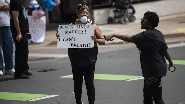 Une femme manifeste en tenant une pancarte sur laquelle il est écrit: «Black Lives Matter! I can't breath».