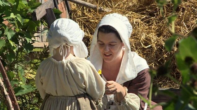 Une femme et un enfant en costumes du 18e siècle pendant un tournage.