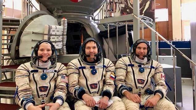 Trois personnes en tenue d'astronaute.