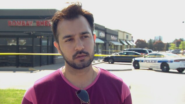 Un homme est debout. Une voiture de police est à droite et le restaurant indien est à gauche. Un homme est debout. Une voiture de police est à droite et le restaurant indien est à gauche.