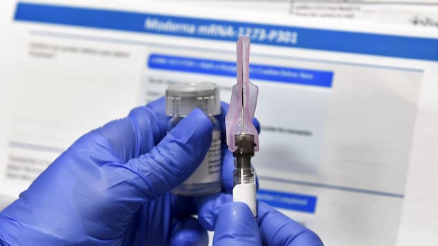 Des mains tiennent une fiole de vaccin et une seringue.