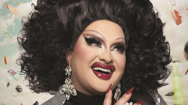 Affiche du spectacle montrant l'humoriste et drag queen entourée d'objets hétéroclites qui virevoltent en l'air. 