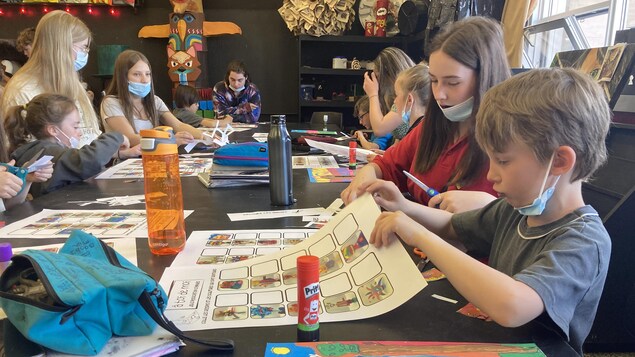 Des jeunes autour d'un bureau avec des dessins.